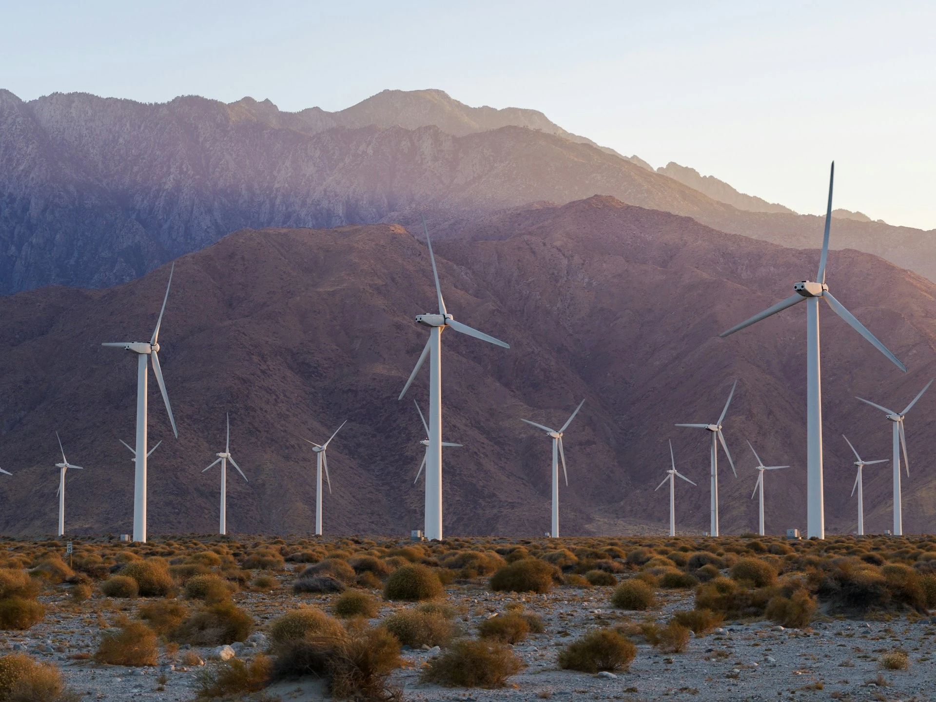 mountain range with wind turbines on top and a sunset in the background